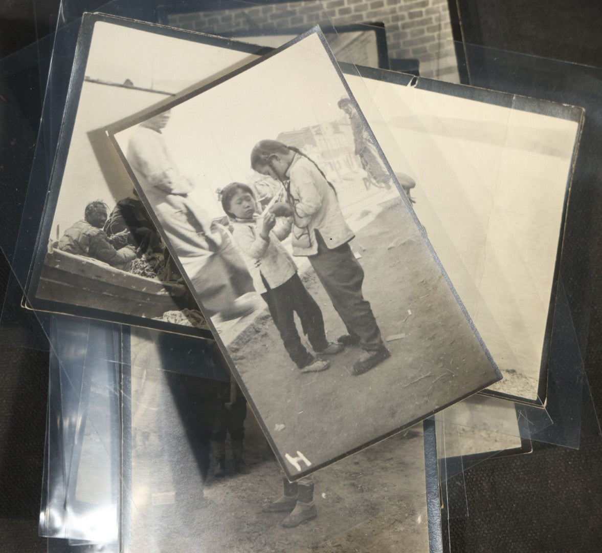 Grouping of 12 Antique Snapshot Photographs, East Asian and Russian-Language Settings including Sword Performer, Street Performer with Knife, Man with Trained Bear, Fishermen with Crabs, Construction Workers, and Children