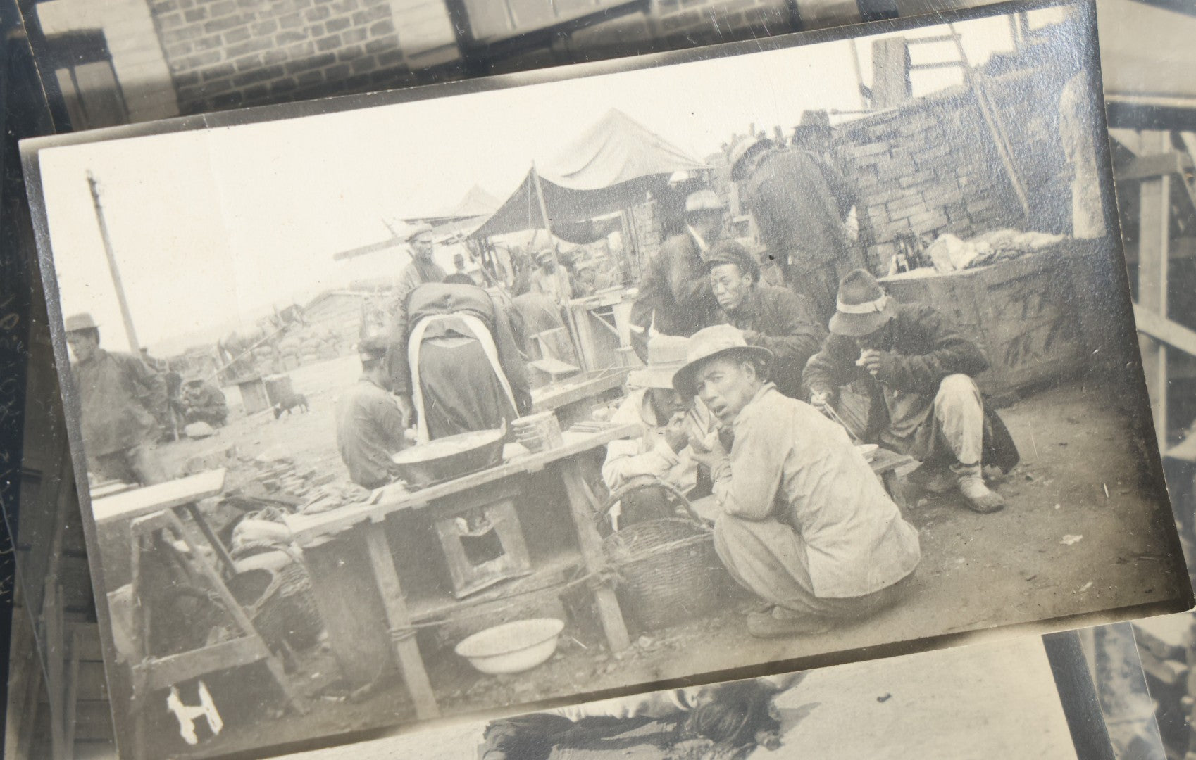 Grouping of 12 Antique Snapshot Photographs, East Asian and Russian-Language Settings including Sword Performer, Street Performer with Knife, Man with Trained Bear, Fishermen with Crabs, Construction Workers, and Children