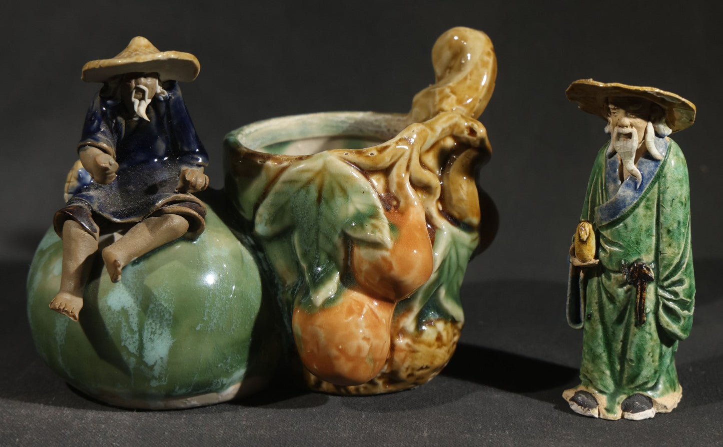 Pair of Vintage Chinese Mudman Ceramic Figurines including Seated Figure on Melon Planter and Standing Elder in Green Robe, Made in China