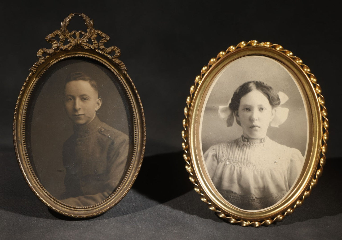 Pair of Antique Framed Oval Portrait Photographs of a Young Soldier and a Young Girl in Brass Frames with Convex Glass