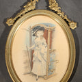 Lot 189 - Vintage French-Style Oval Brass Frame with Ribbon and Garland Crest, Colored Print of a Woman Exiting a Sedan Chair, 4-3/4" W x 9" H