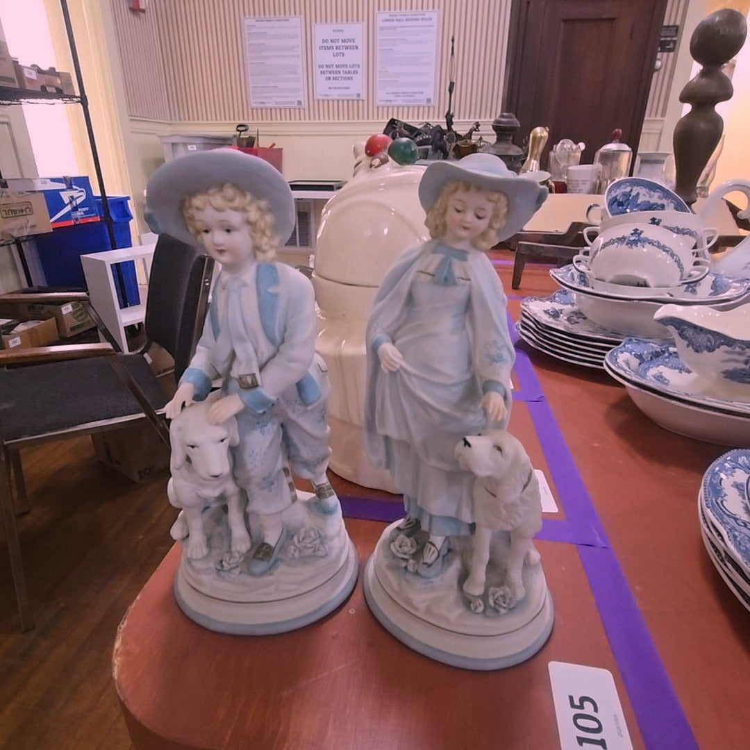 two bisque statues of children with dogs