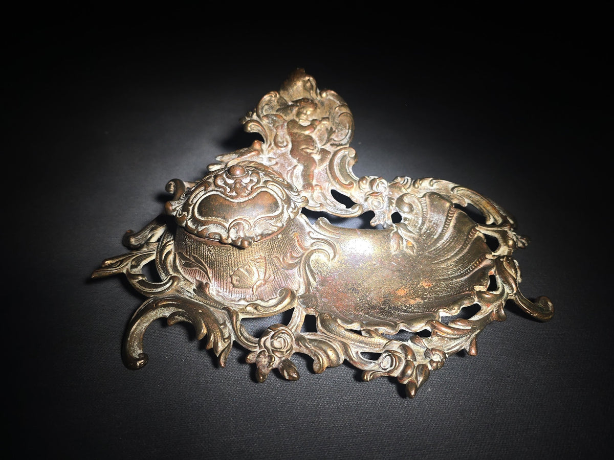 Antique Cast Metal Rococo-Style Inkstand with Cherub Finial, Glass Ink Insert, Hinged Lid, and Shell-Form Pen Tray