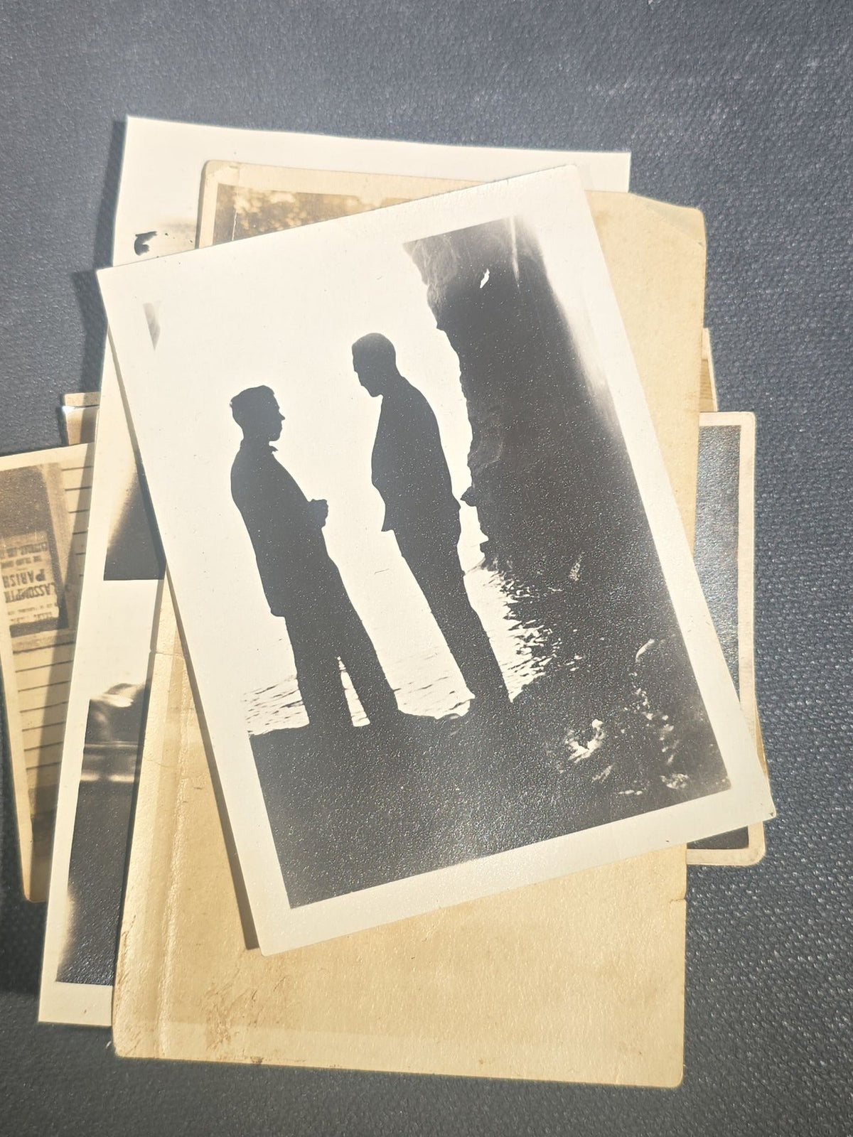 Grouping of Eight Antique and Vintage Snapshot Photographs including Boys Gambling on a Sidewalk, Clown on Stoop, Silhouette of Two Figures on a Shore, and a Group Portrait Outside