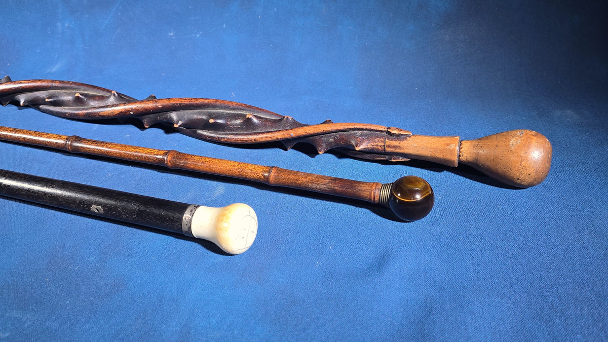 Trio of Antique Walking Canes including Carved Twisted Wood, Bamboo with Tiger's Eye Ball Top, and Ivory-Topped Ebony