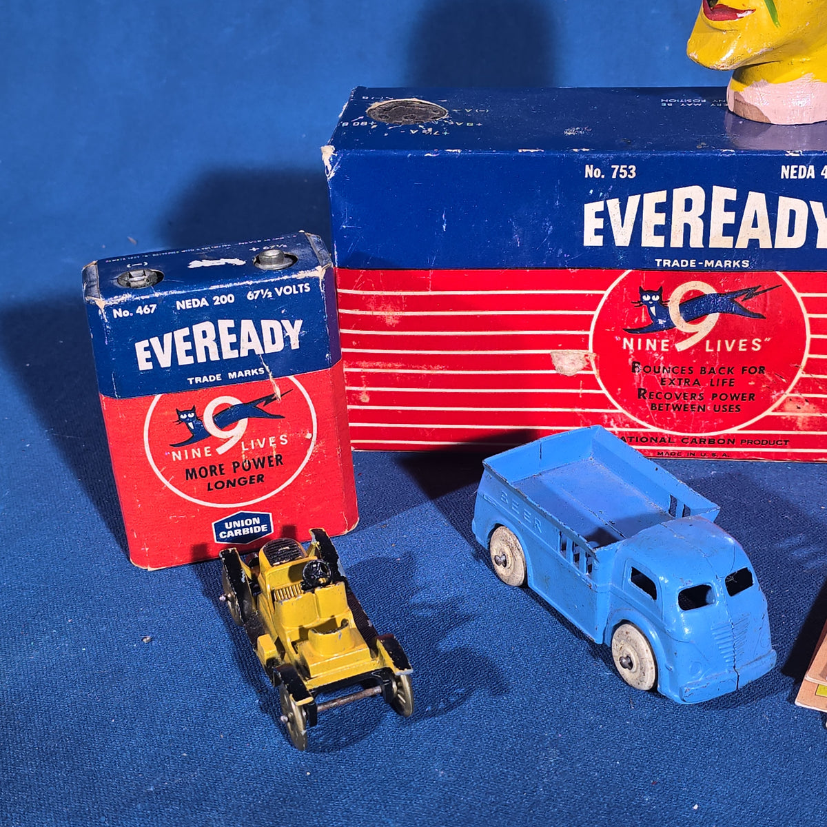 Grouping of Vintage Smalls including Eveready Nine Lives Batteries, Cast Metal Toy Cars, Carved Wooden Devil Head, and Postcards