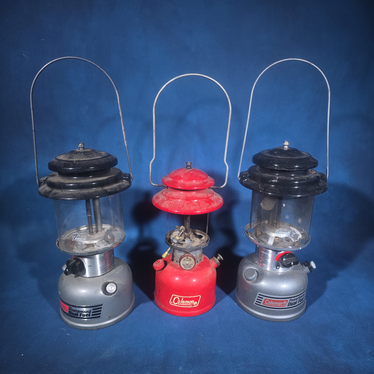 Trio of Vintage and Modern Coleman Camping Lanterns including Red Single-Mantle and Two Powerhouse Dual Fuel Models