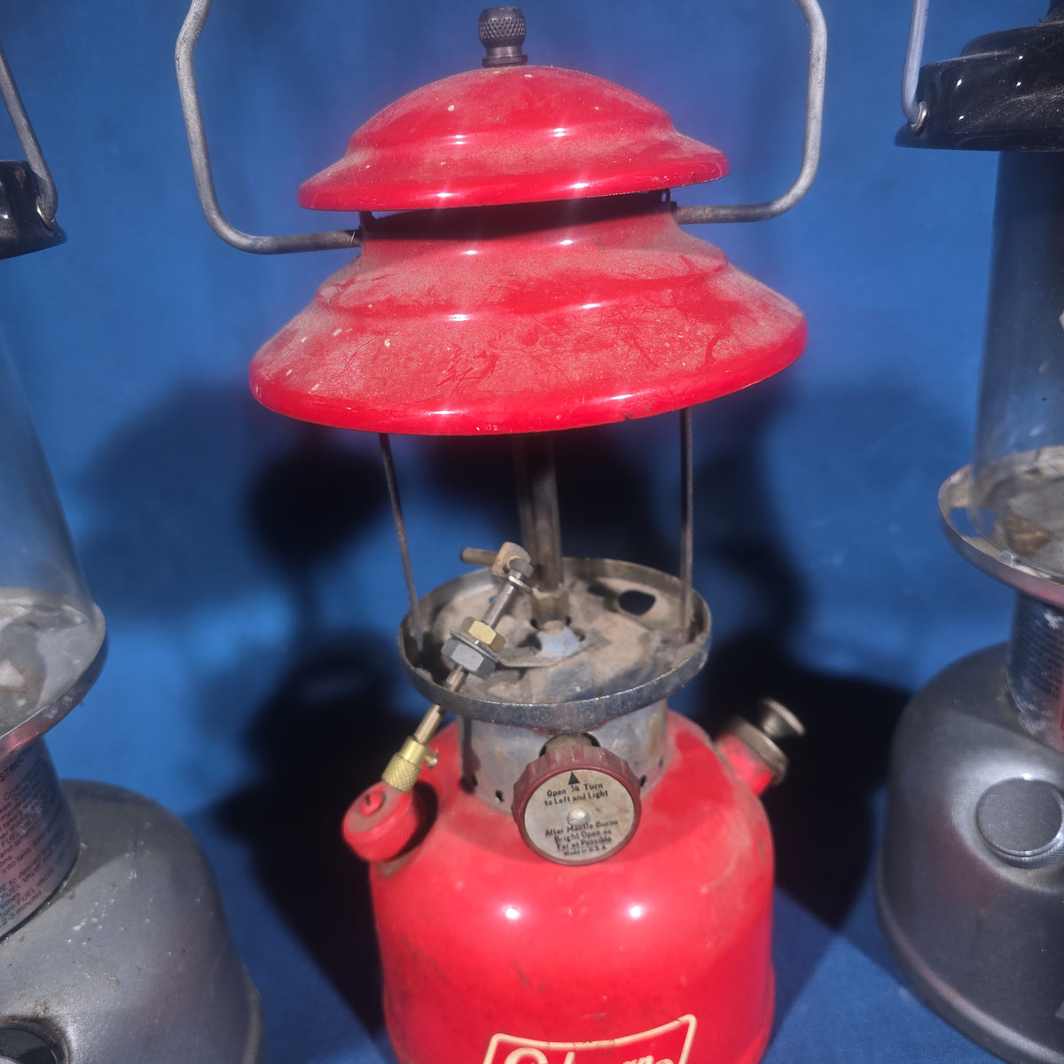 Trio of Vintage and Modern Coleman Camping Lanterns including Red Single-Mantle and Two Powerhouse Dual Fuel Models