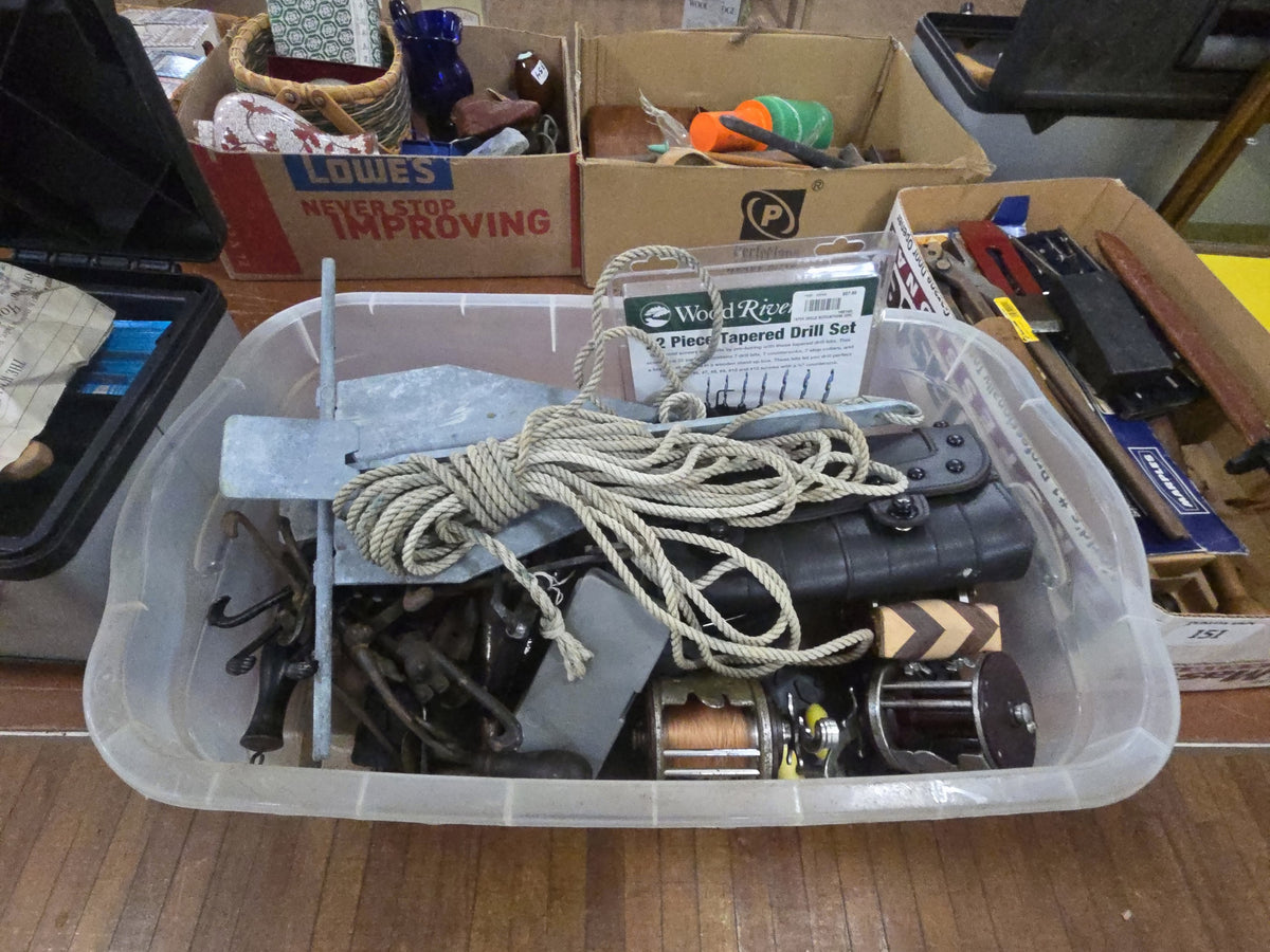 box lot of miscellaneous items including tools, fishing reels, anchor, and cast iron monkeys