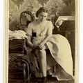 Lot 013 - Antique Risque Carte De Visite C.D.V. Photograph of a Partially Nude Woman Seated on a Bed with Exposed Breast, Wearing a Cross Necklace and Stockings