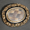 Lot 005 - Antique Victorian Hair Work Keepsake Brooch with Woven Hair Under Glass, Black Enamel Border with Gold-Tone Scroll Frame and Pendant Loop