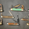 Lot 079 - Grouping of Seven Vintage Folding Pocket Knives Including Multi-Tool Camp Knives, Stockman, and Trapper Styles with Bone, Jigged, and Composite Handles