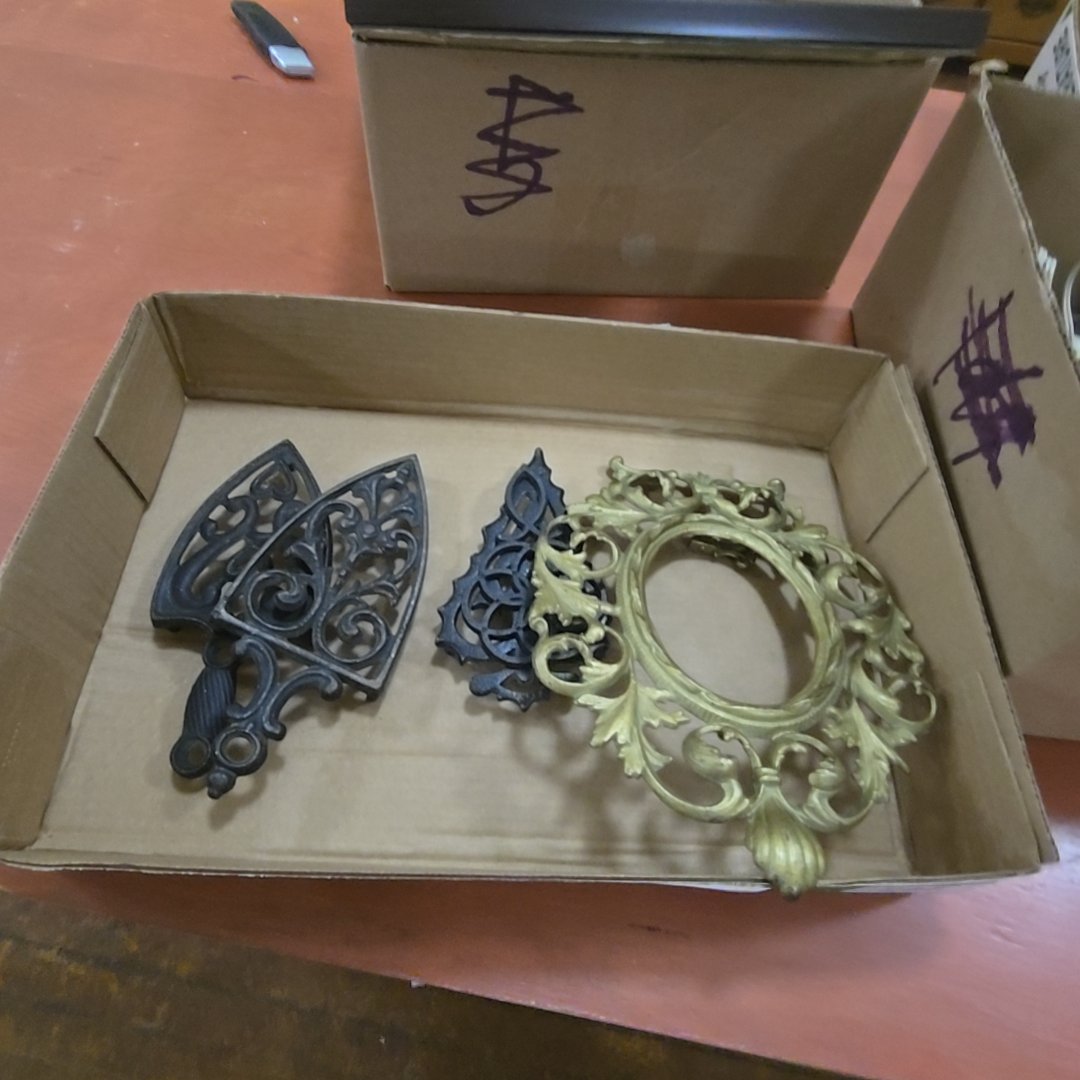 box lot with cast iron trivets, and gold painted cast iron frame