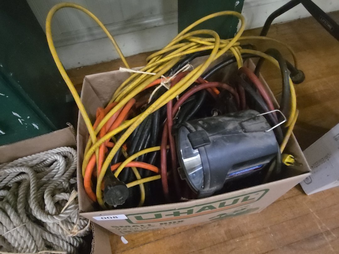 box lot with extension cords, jumper cables, and work light