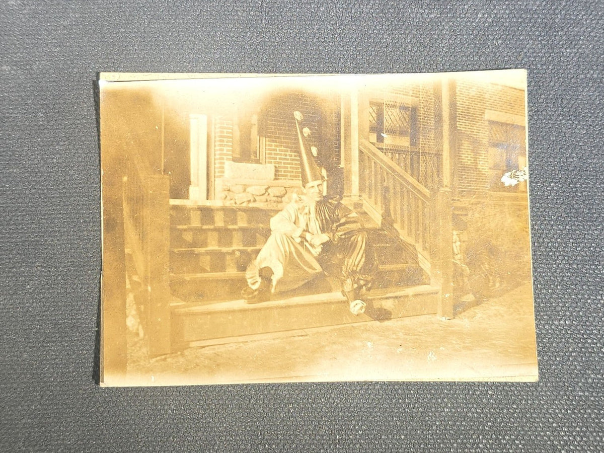 Grouping of Eight Antique and Vintage Snapshot Photographs including Boys Gambling on a Sidewalk, Clown on Stoop, Silhouette of Two Figures on a Shore, and a Group Portrait Outside