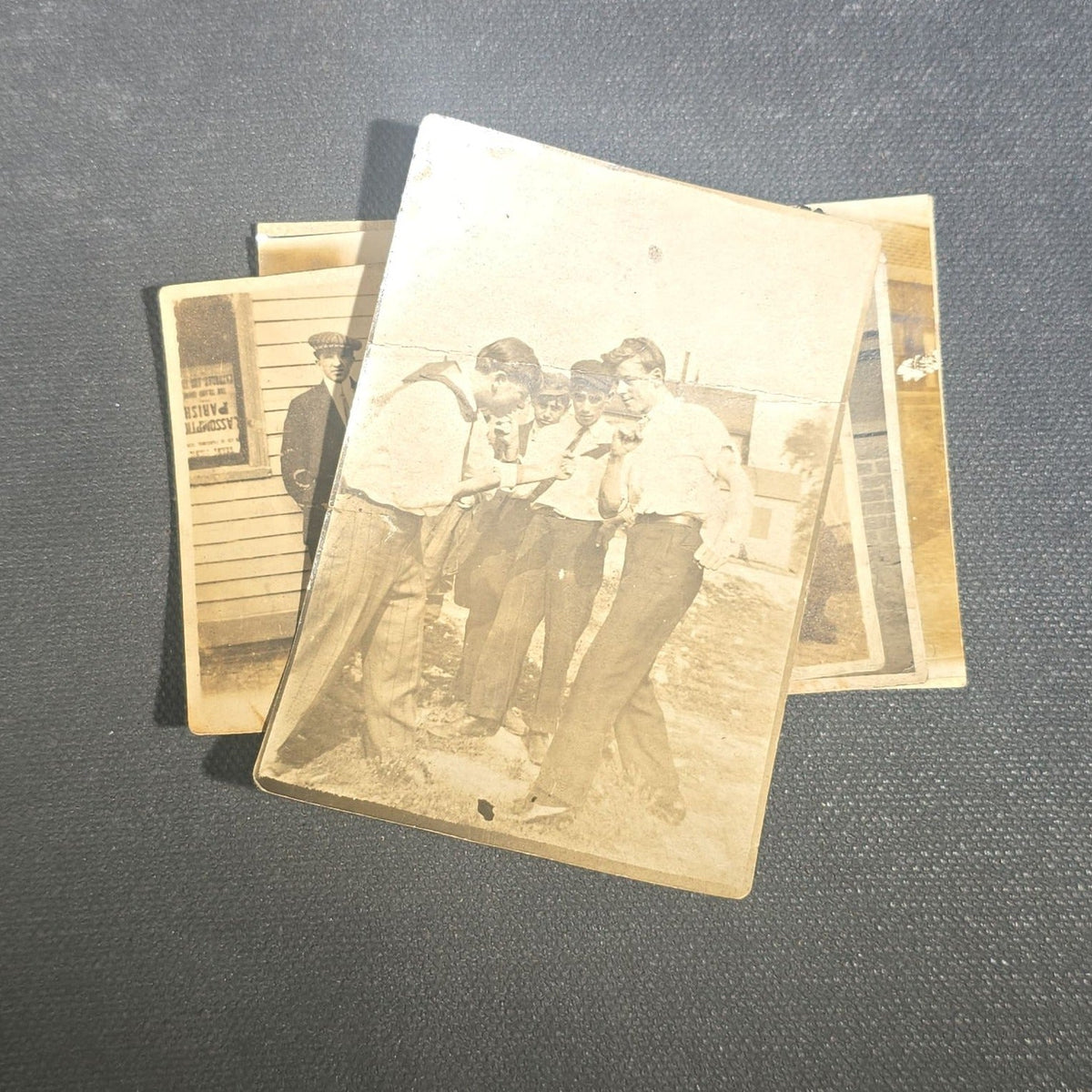 Grouping of Eight Antique and Vintage Snapshot Photographs including Boys Gambling on a Sidewalk, Clown on Stoop, Silhouette of Two Figures on a Shore, and a Group Portrait Outside