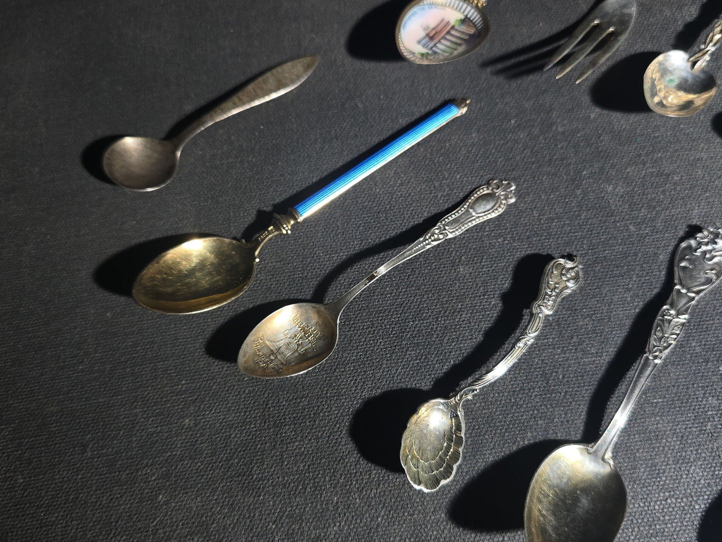 Grouping of 24 Antique and Vintage Sterling, 800 Silver, and Silver-Plated Souvenir and Collector's Spoons and Cutlery including 23 Spoons and One Fork