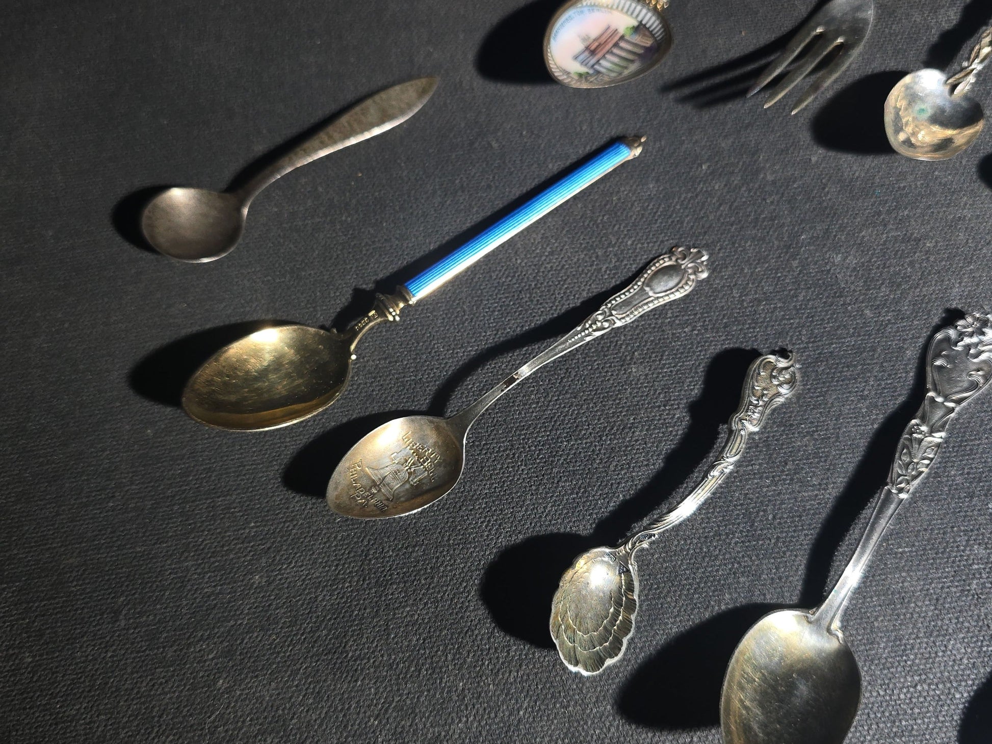 Grouping of 24 Antique and Vintage Sterling, 800 Silver, and Silver-Plated Souvenir and Collector's Spoons and Cutlery including 23 Spoons and One Fork