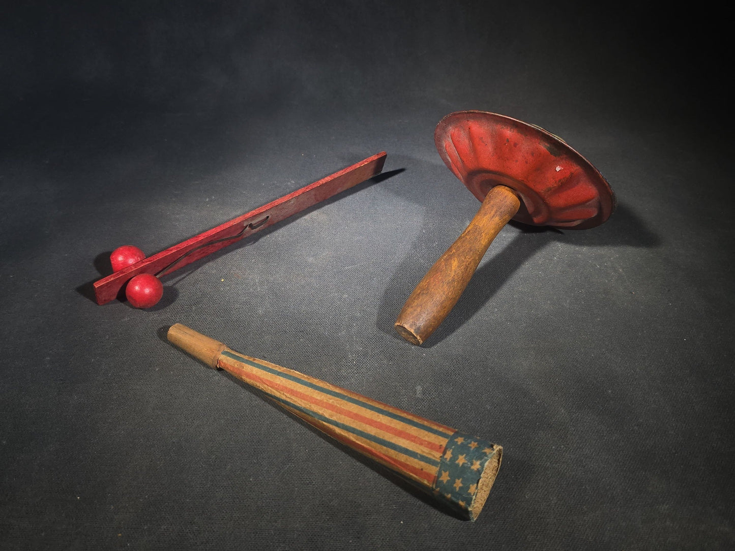Trio of Antique Patriotic Noisemakers including Tin Lithograph Noisemaker with Stars and Stripes, Paper Horn, and Red Wooden Ball Clapper