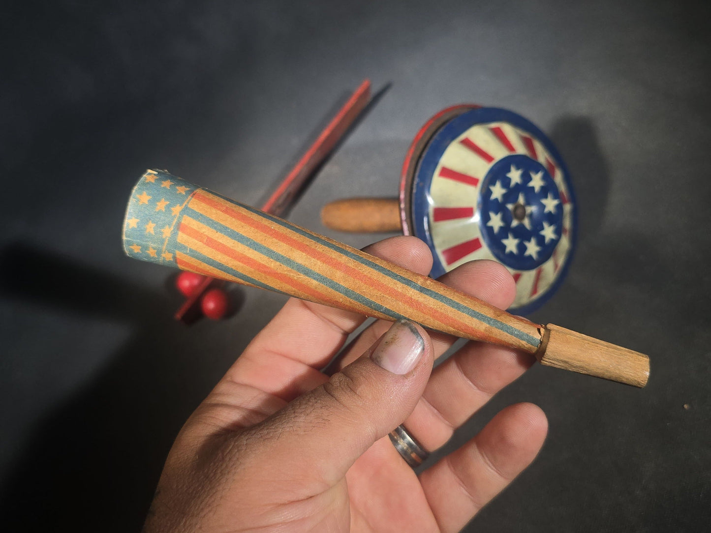 Trio of Antique Patriotic Noisemakers including Tin Lithograph Noisemaker with Stars and Stripes, Paper Horn, and Red Wooden Ball Clapper