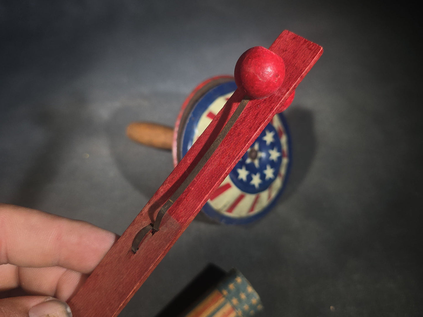 Trio of Antique Patriotic Noisemakers including Tin Lithograph Noisemaker with Stars and Stripes, Paper Horn, and Red Wooden Ball Clapper