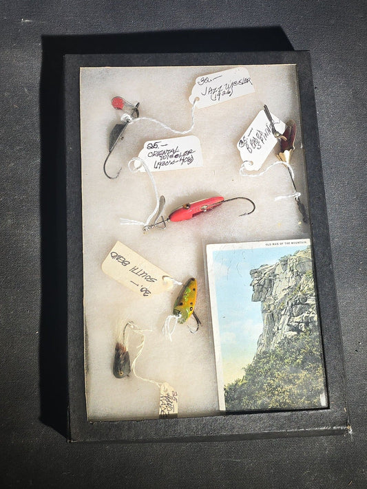 Grouping of Antique and Vintage Fishing Lures in Riker Display Case including Jazz Wiggler, Oriental Wiggler, Bladed Spinner, and South Bend, with Old Man of the Mountain Postcard