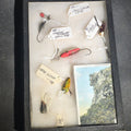 Lot 067 - Grouping of Antique and Vintage Fishing Lures in Riker Display Case Including Jazz Wiggler, Oriental Wiggler, Bladed Spinner, and South Bend, with Old Man of the Mountain Postcard