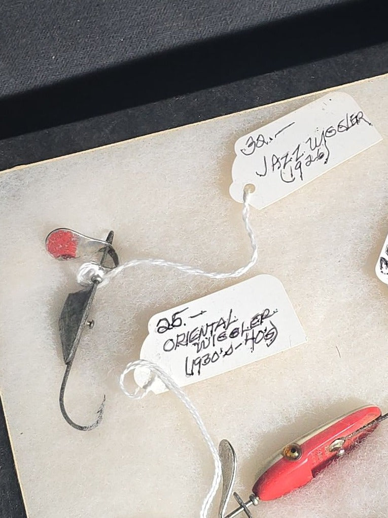 Grouping of Antique and Vintage Fishing Lures in Riker Display Case including Jazz Wiggler, Oriental Wiggler, Bladed Spinner, and South Bend, with Old Man of the Mountain Postcard