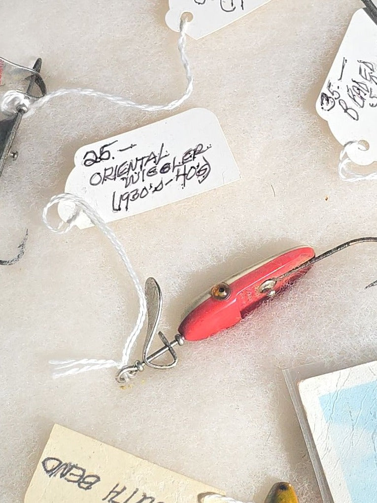 Grouping of Antique and Vintage Fishing Lures in Riker Display Case including Jazz Wiggler, Oriental Wiggler, Bladed Spinner, and South Bend, with Old Man of the Mountain Postcard