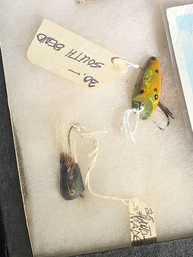 Grouping of Antique and Vintage Fishing Lures in Riker Display Case including Jazz Wiggler, Oriental Wiggler, Bladed Spinner, and South Bend, with Old Man of the Mountain Postcard