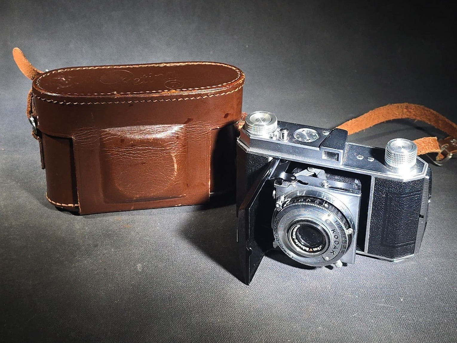 Pair of Antique and Vintage Kodak Folding Cameras including No. 1A Pocket Kodak Series II in Red with Kodak Anastigmat Lens and Kodak Retina 35mm Camera with Schneider-Kreuznach Xenar Lens, Compur-Rapid Shutter, and Leather Case