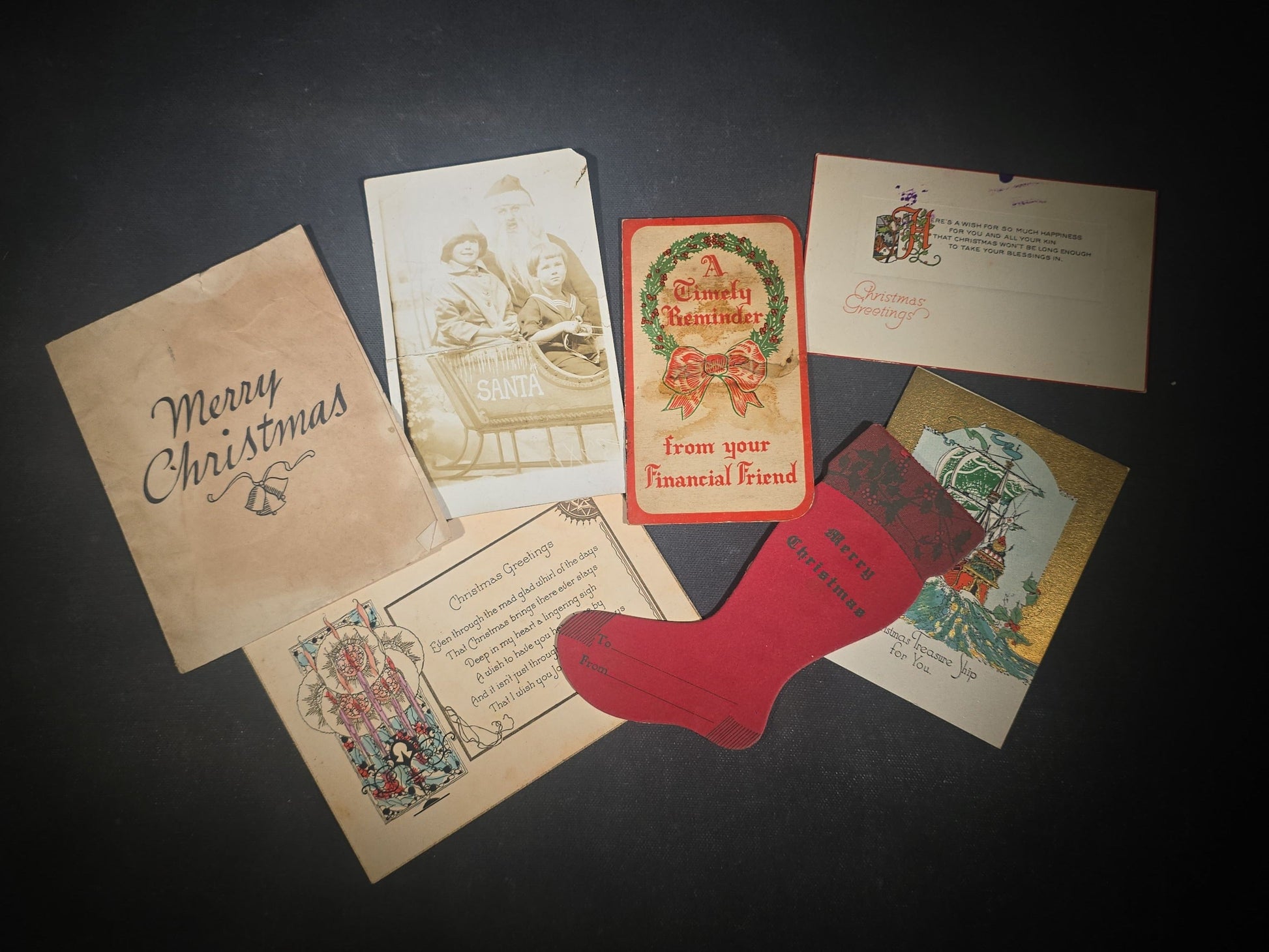 Grouping of Seven Antique and Vintage Christmas Ephemera including Santa Claus with Children in Sleigh R.P.P.C., Quincy Savings Bank Die-Cut Stocking Dime Holder, Personal Finance Company Advertising Needle Case, and Anti-New Deal Humorous Poem