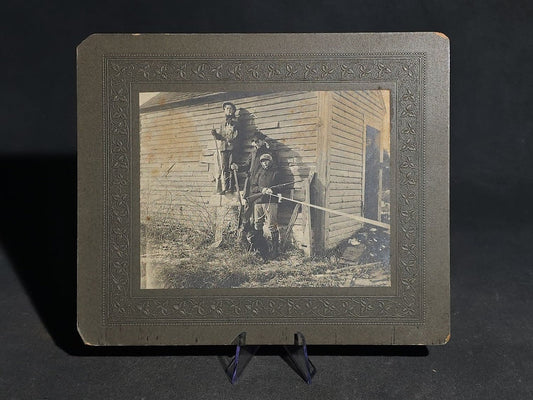 Antique Board-Mounted "Selfie" Photograph of Three Hunters with Rifles and Game Posed Outside a Wooden Building, Self-Timed Shutter Release