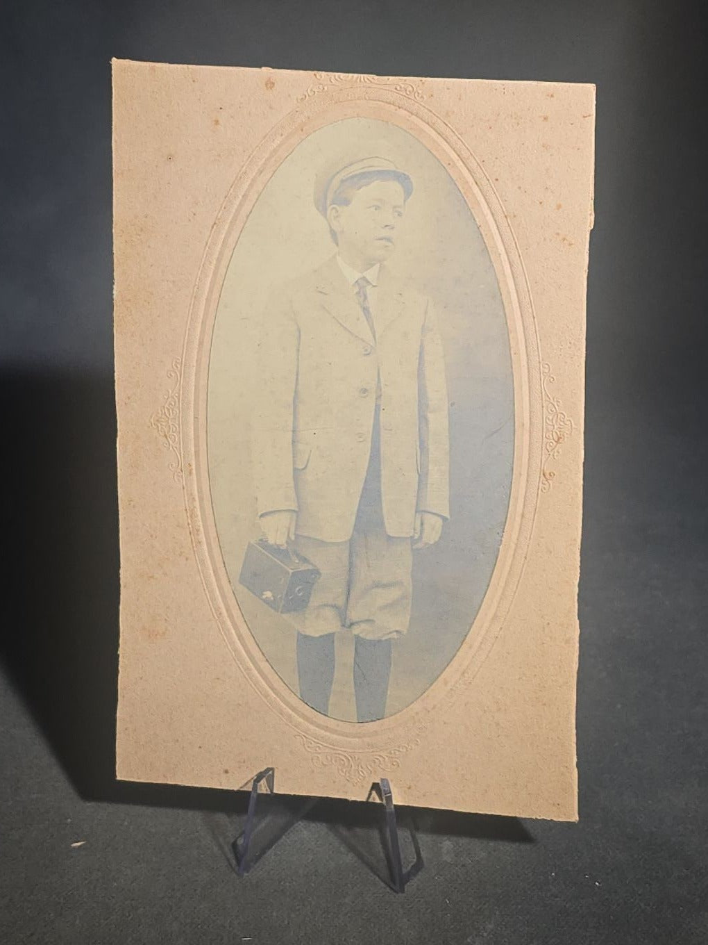 Grouping of Five Antique and Vintage Board-Mounted Photographs including Boy Holding a Box Camera, Two Men in Uniform, Family Eating Watermelon, and Dog Looking Out a Window, One Photographed by Rogers, New Haven, Connecticut