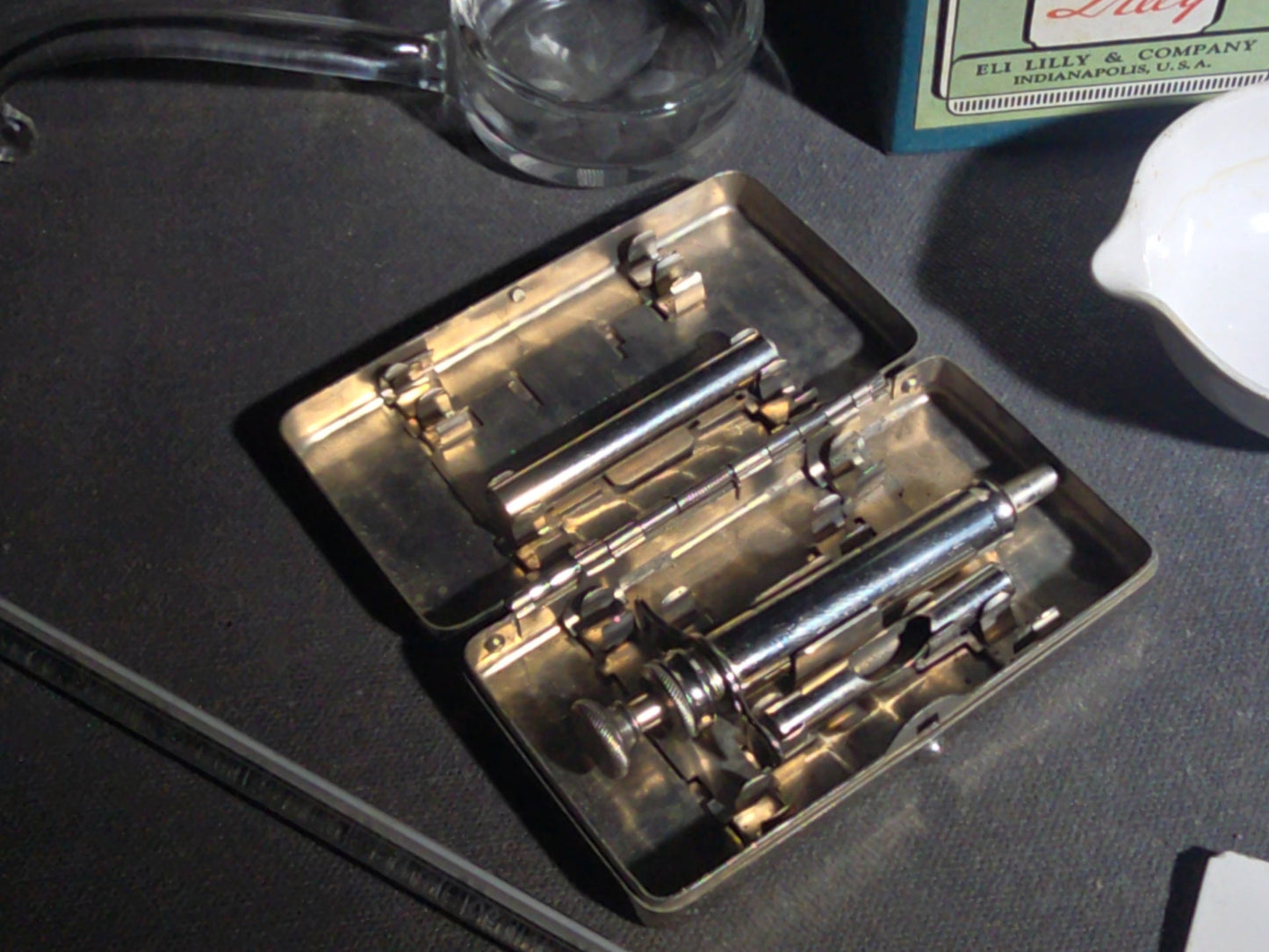 Grouping of Vintage Dental and Medical Pieces including Eli Lilly Merthiolate Twin Refill Box, Glass Syringe, and Chrome Dental Aspirating Syringe