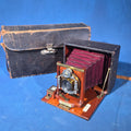 Lot 095 - Antique Sears, Roebuck & Co. Mahogany Folding Plate Camera with Bausch & Lomb Unicum Shutter, Red Bellows, and Leather Carrying Case, 11" L