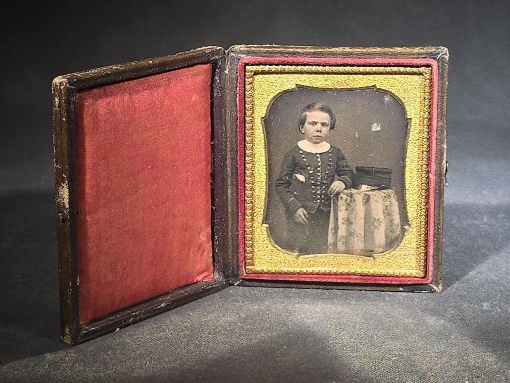 Antique 1/6th Plate Daguerreotype Photograph of a Child Standing Beside a Cloth-Covered Table with a Cap in Full Intact Leatherette Union Case with Embossed Floral and Scroll Design