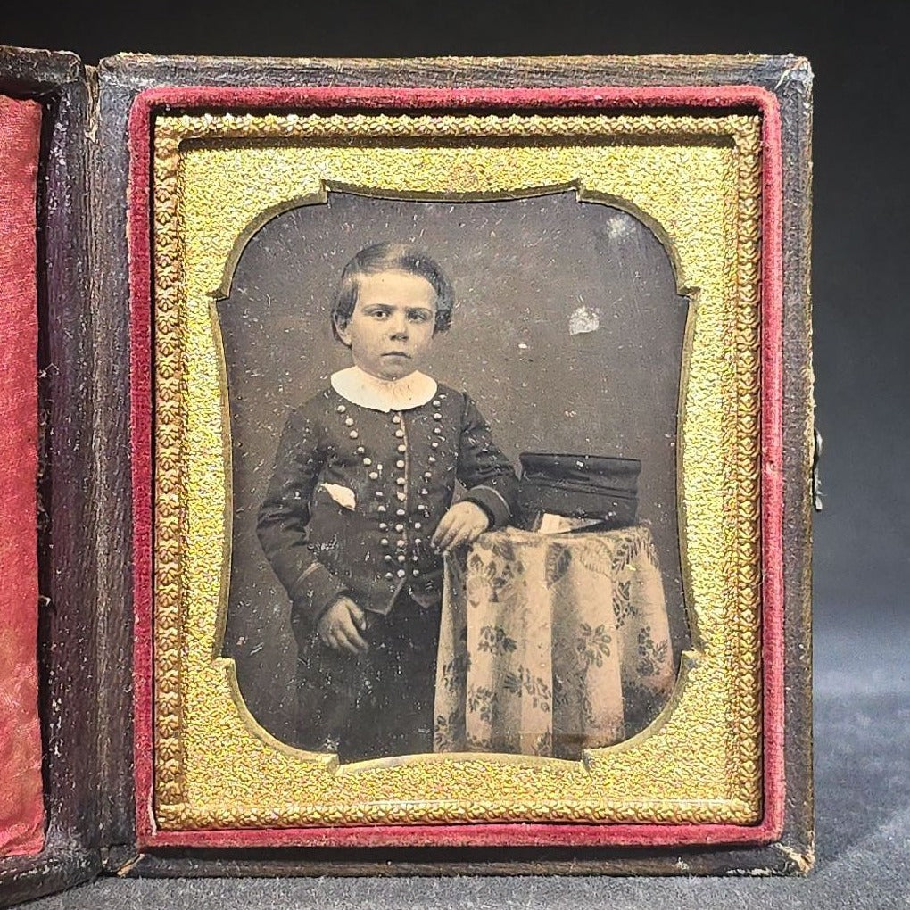 Antique 1/6th Plate Daguerreotype Photograph of a Child Standing Beside a Cloth-Covered Table with a Cap in Full Intact Leatherette Union Case with Embossed Floral and Scroll Design