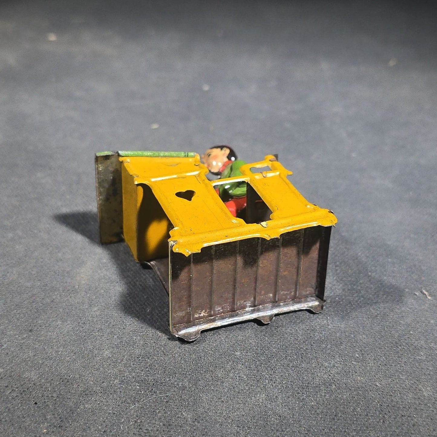 Grouping of Four Antique and Vintage Tin Lithograph Miniature Toys including Student at Desk, Two Miniature Travel Suitcases with Hotel and Travel Labels, and Pair of Seated Figures in Helmets
