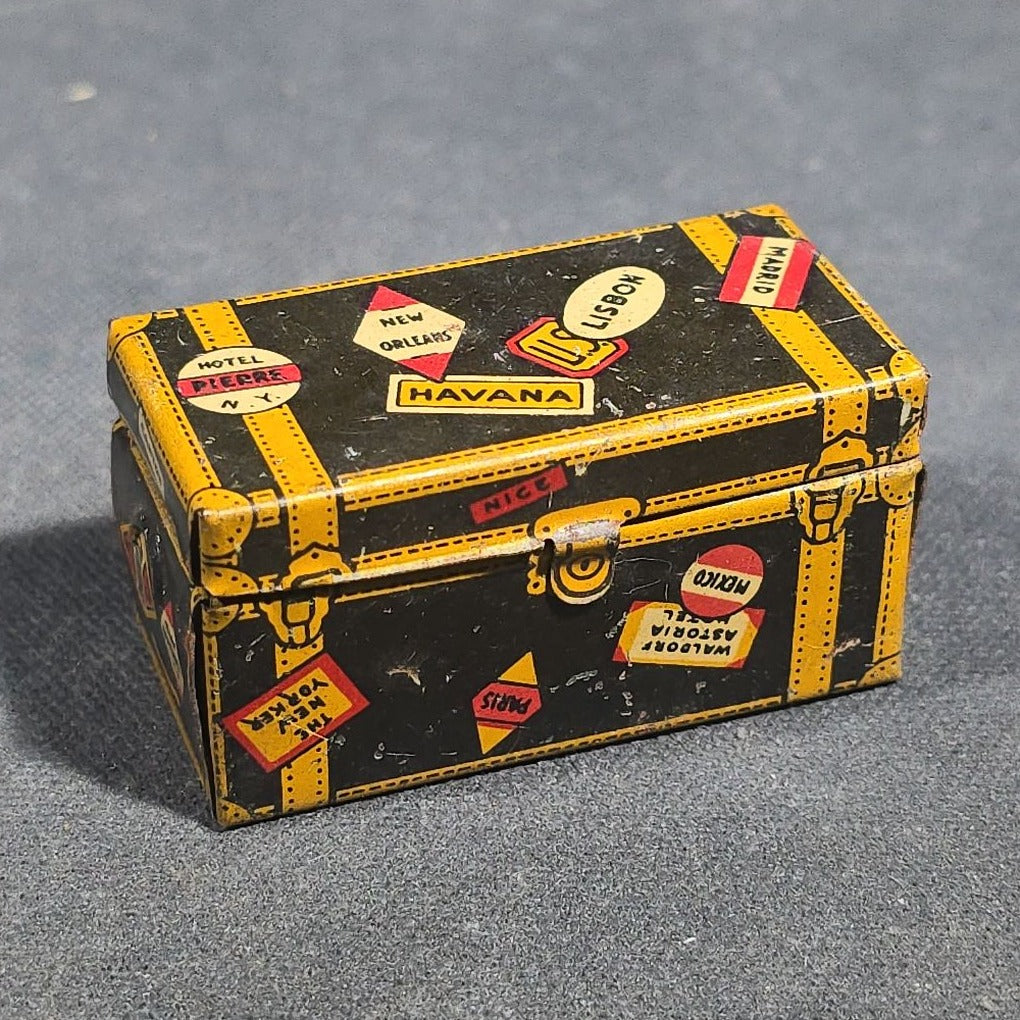 Grouping of Four Antique and Vintage Tin Lithograph Miniature Toys including Student at Desk, Two Miniature Travel Suitcases with Hotel and Travel Labels, and Pair of Seated Figures in Helmets
