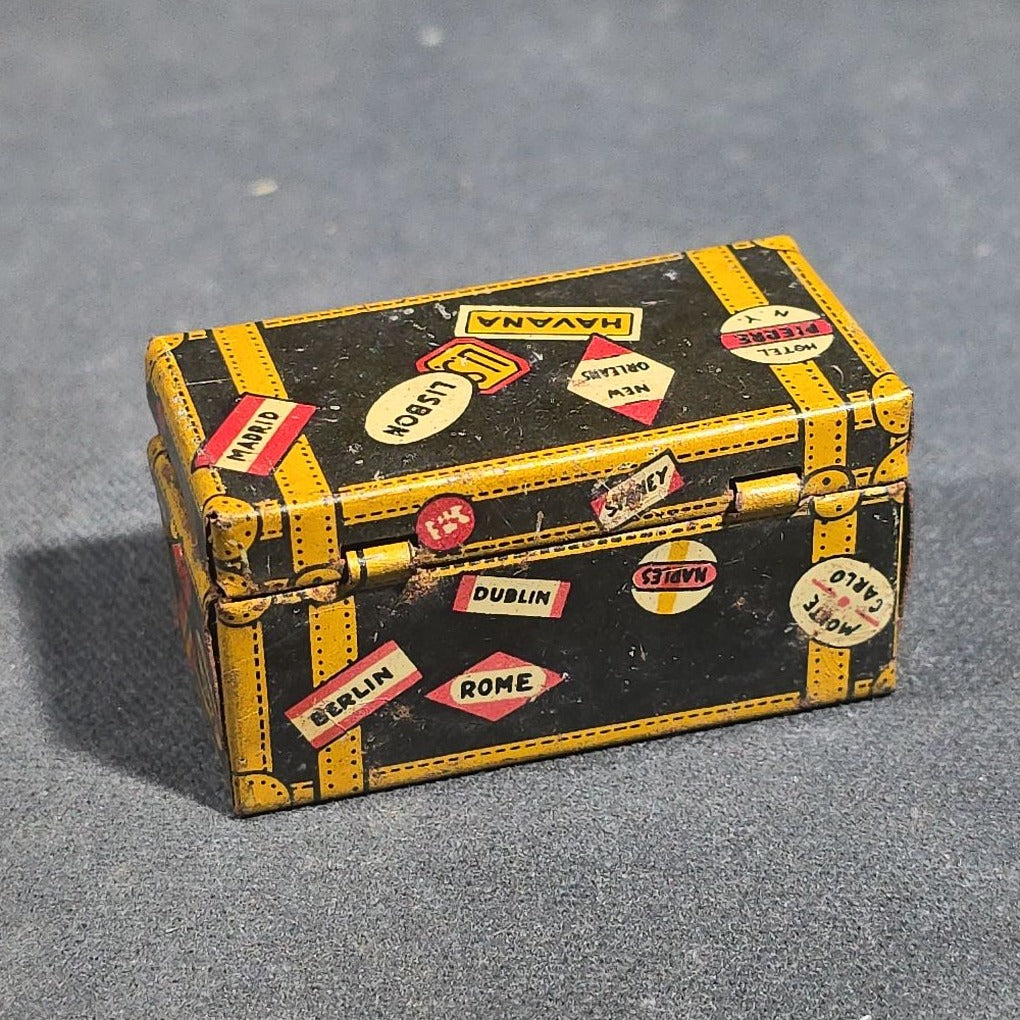 Grouping of Four Antique and Vintage Tin Lithograph Miniature Toys including Student at Desk, Two Miniature Travel Suitcases with Hotel and Travel Labels, and Pair of Seated Figures in Helmets