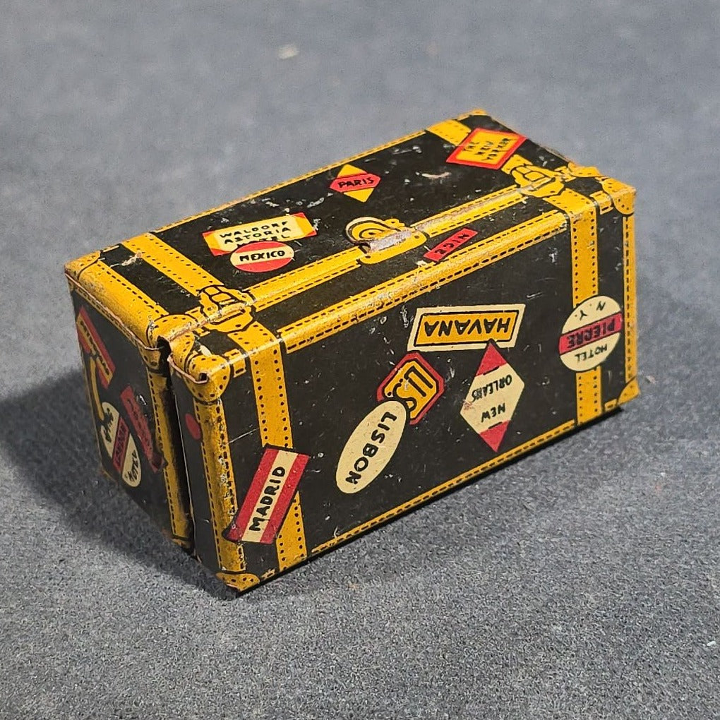 Grouping of Four Antique and Vintage Tin Lithograph Miniature Toys including Student at Desk, Two Miniature Travel Suitcases with Hotel and Travel Labels, and Pair of Seated Figures in Helmets