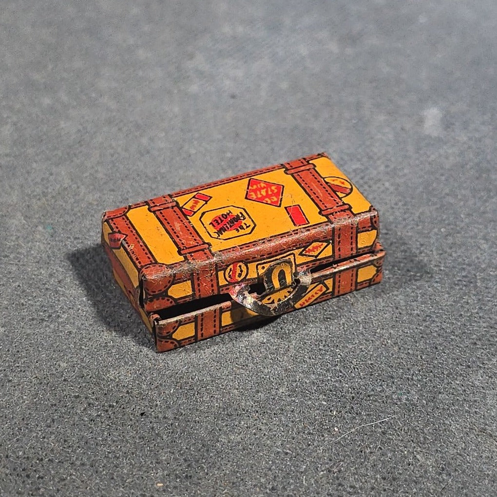 Grouping of Four Antique and Vintage Tin Lithograph Miniature Toys including Student at Desk, Two Miniature Travel Suitcases with Hotel and Travel Labels, and Pair of Seated Figures in Helmets