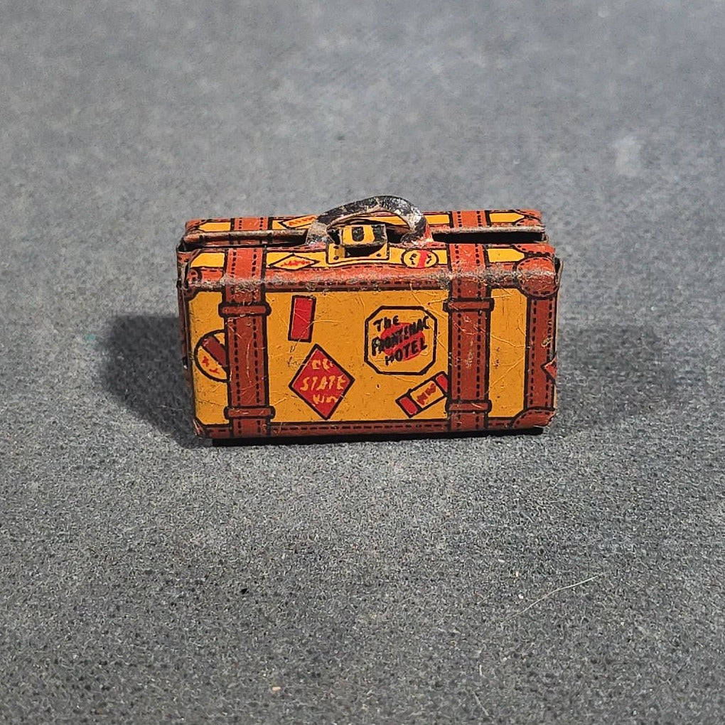 Grouping of Four Antique and Vintage Tin Lithograph Miniature Toys including Student at Desk, Two Miniature Travel Suitcases with Hotel and Travel Labels, and Pair of Seated Figures in Helmets