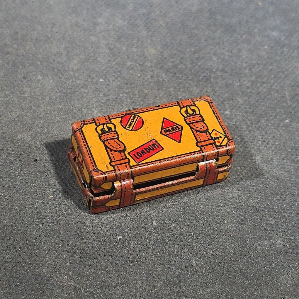 Grouping of Four Antique and Vintage Tin Lithograph Miniature Toys including Student at Desk, Two Miniature Travel Suitcases with Hotel and Travel Labels, and Pair of Seated Figures in Helmets