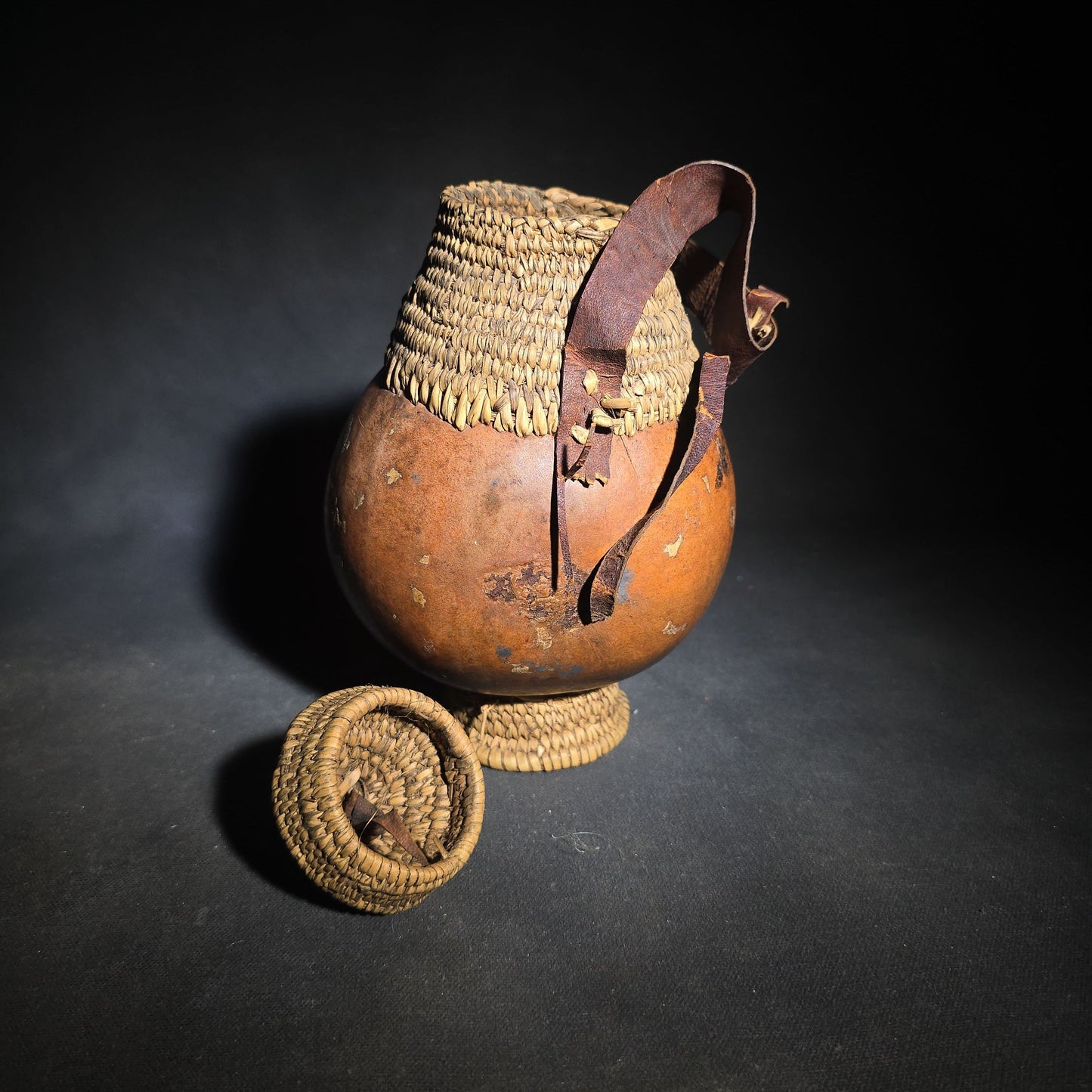Pair of Vintage Woven Baskets including a Gourd Vessel with Leather Strap and Woven Stopper and a Coiled Lidded Basket