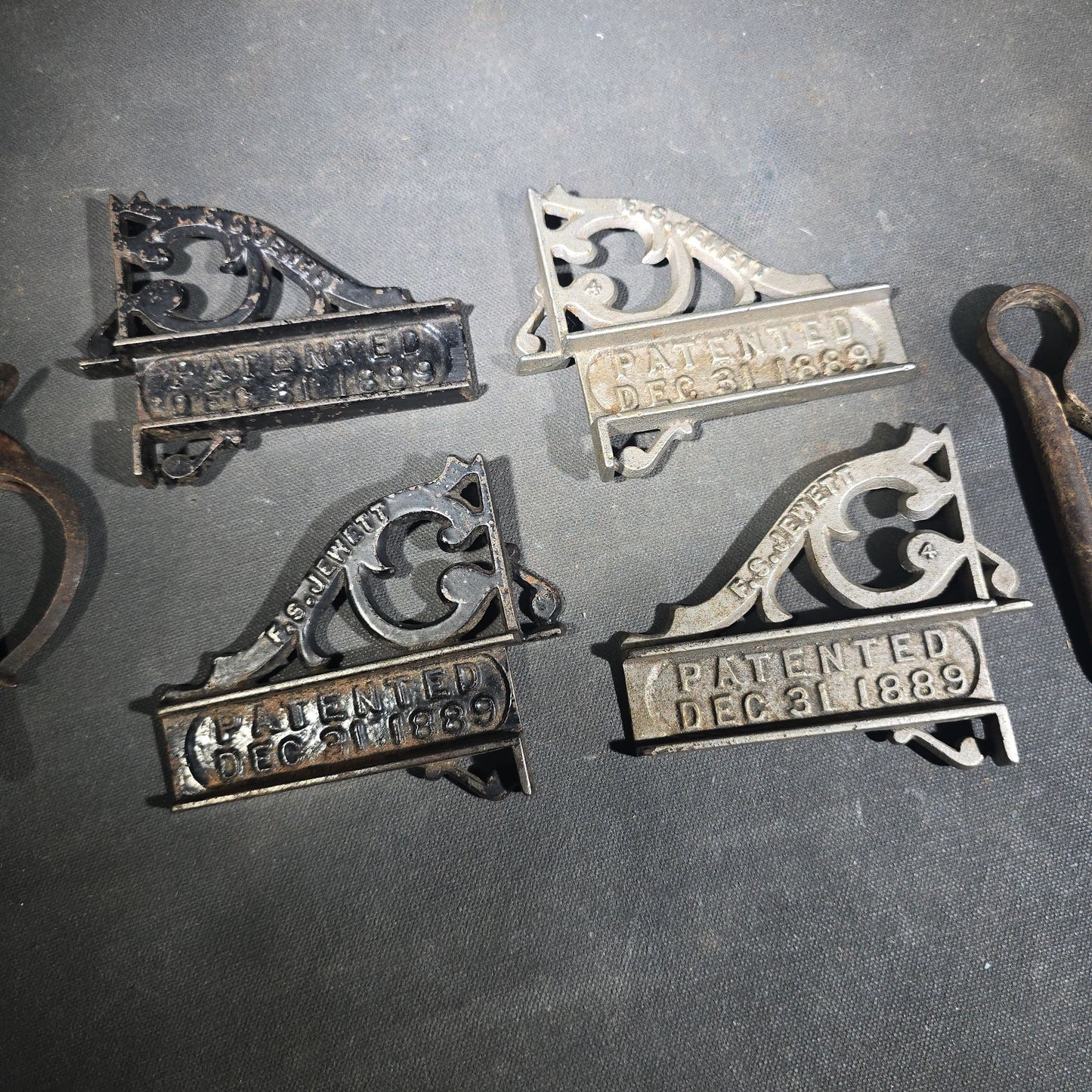 Grouping of Seven Antique Iron Hardware Pieces including Four R.S. Jewett Ornate Shelf Brackets Patented December 31, 1889, a Swivel Ring, and Two Cotter Pins