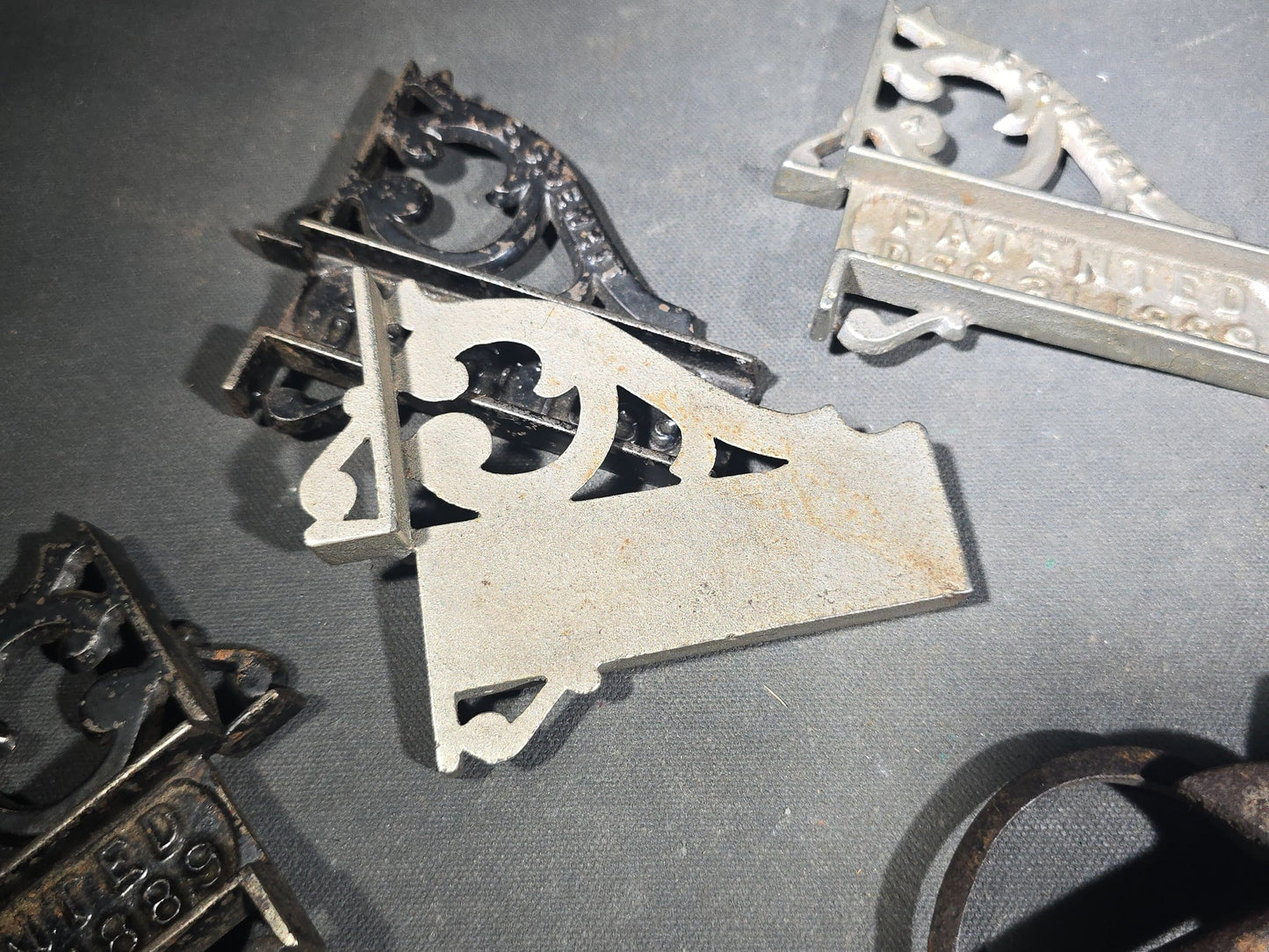 Grouping of Seven Antique Iron Hardware Pieces including Four R.S. Jewett Ornate Shelf Brackets Patented December 31, 1889, a Swivel Ring, and Two Cotter Pins