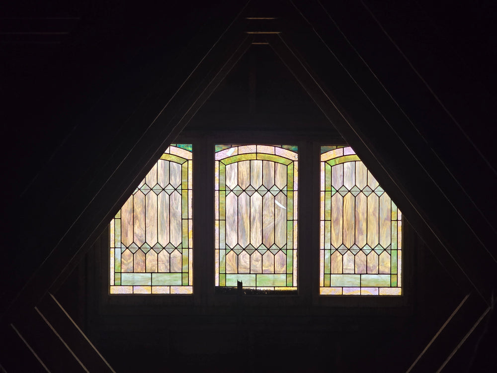 The lone stained-glass window in the attic among the rafters