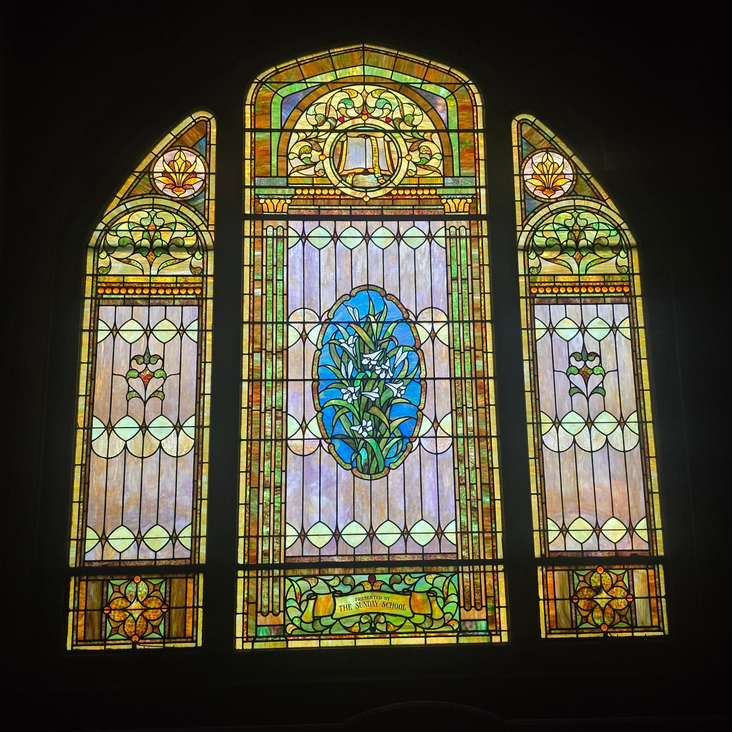 Interior of the main hall with a stained-glass window presented by the Sunday School